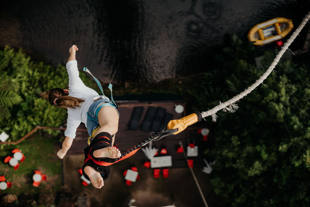 A woman captured mid-air in a bungy jump, with the photo taken from the vantage point where she leaped off.